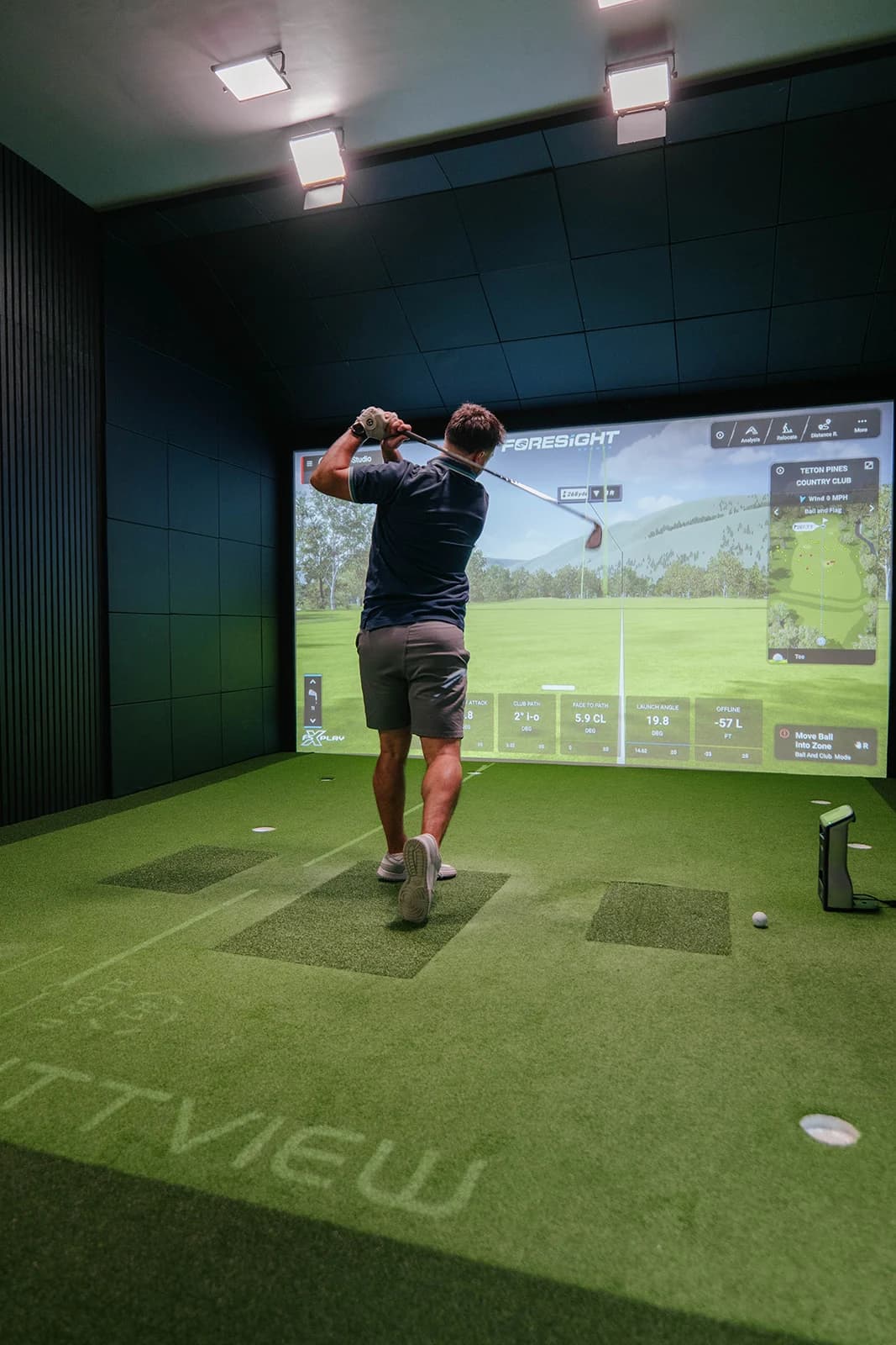 A golfer finishing a shot into the simulator screen above the PuttView floor