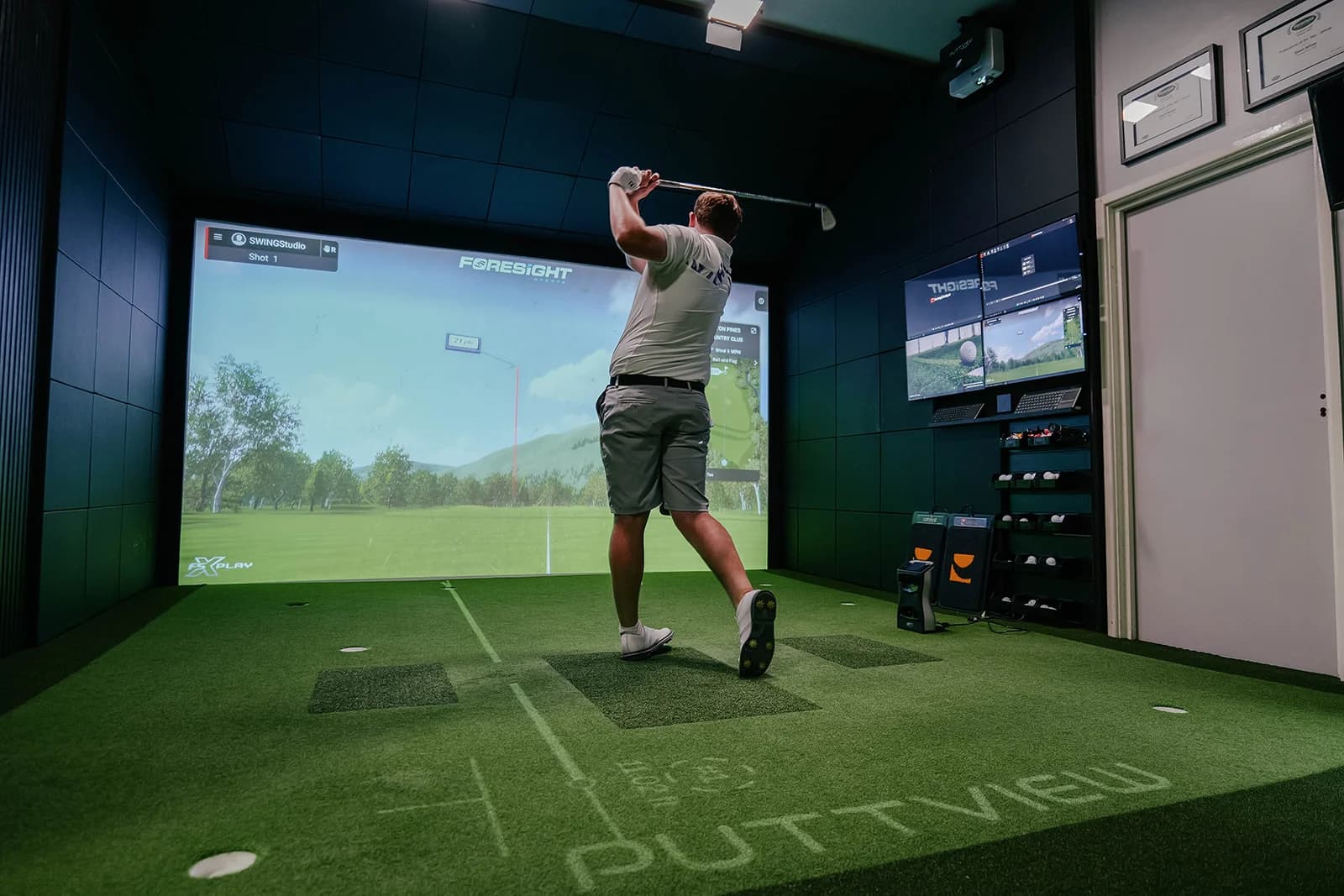 A golfer mid swing into the simulator screen