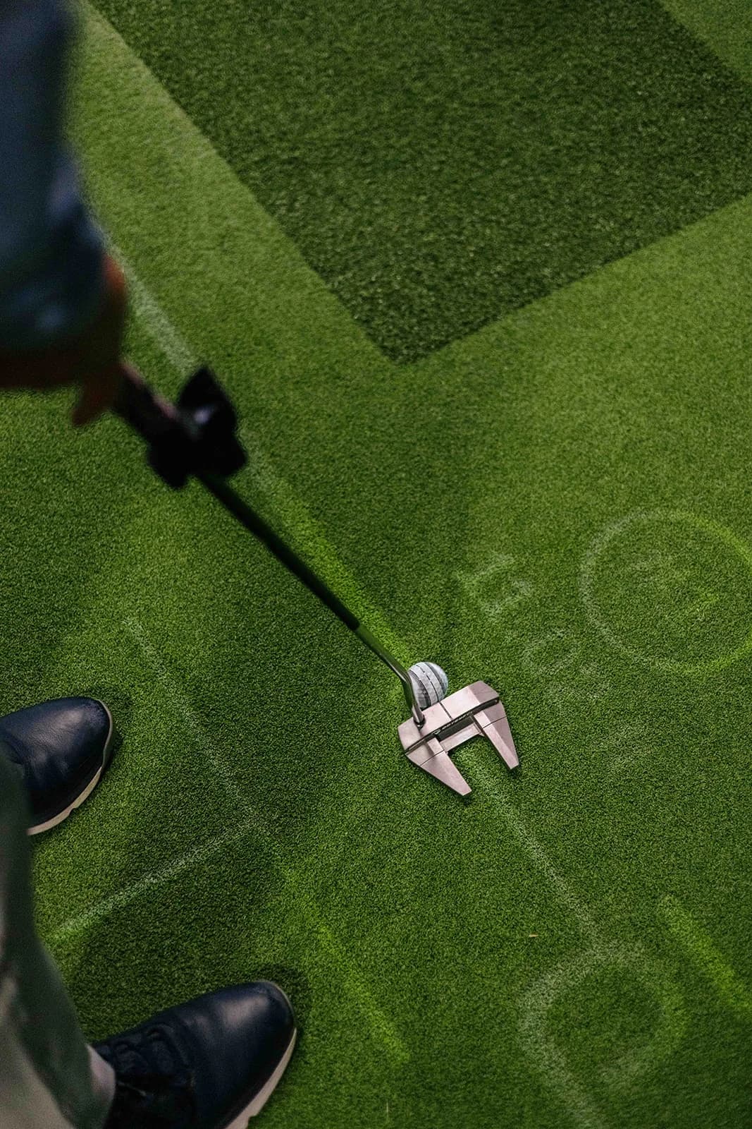 Looking down on a putter set behind the ball on the contoured PuttView green, with projected target markings on the surface