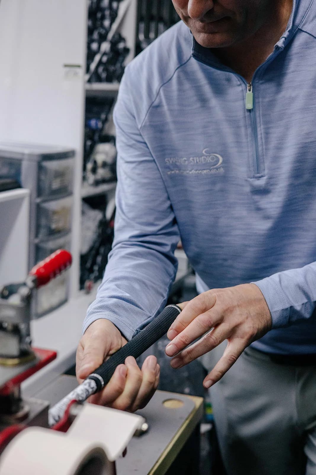 Stuart Wilson sliding a new grip onto a club held in the workshop vice